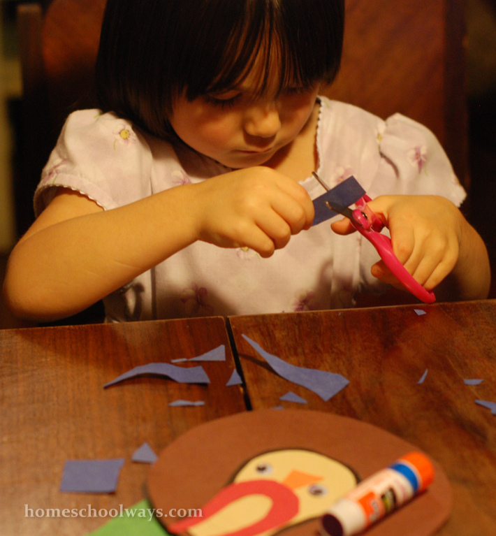 Small girl cutting paper with pink scissors