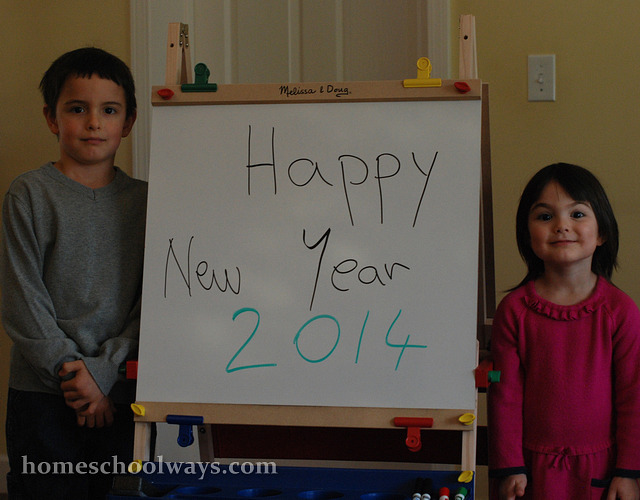 Children wishing a happy new year 2014 in front of a white board