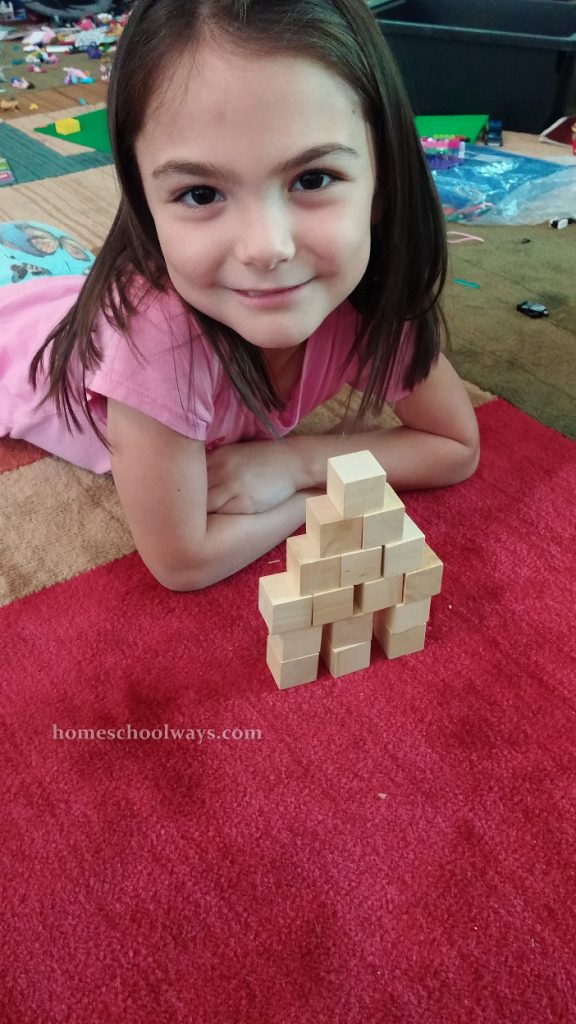 Girl stacks a wooden block tower