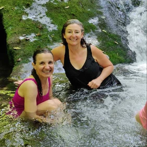 Women sitting in cold mountain river water