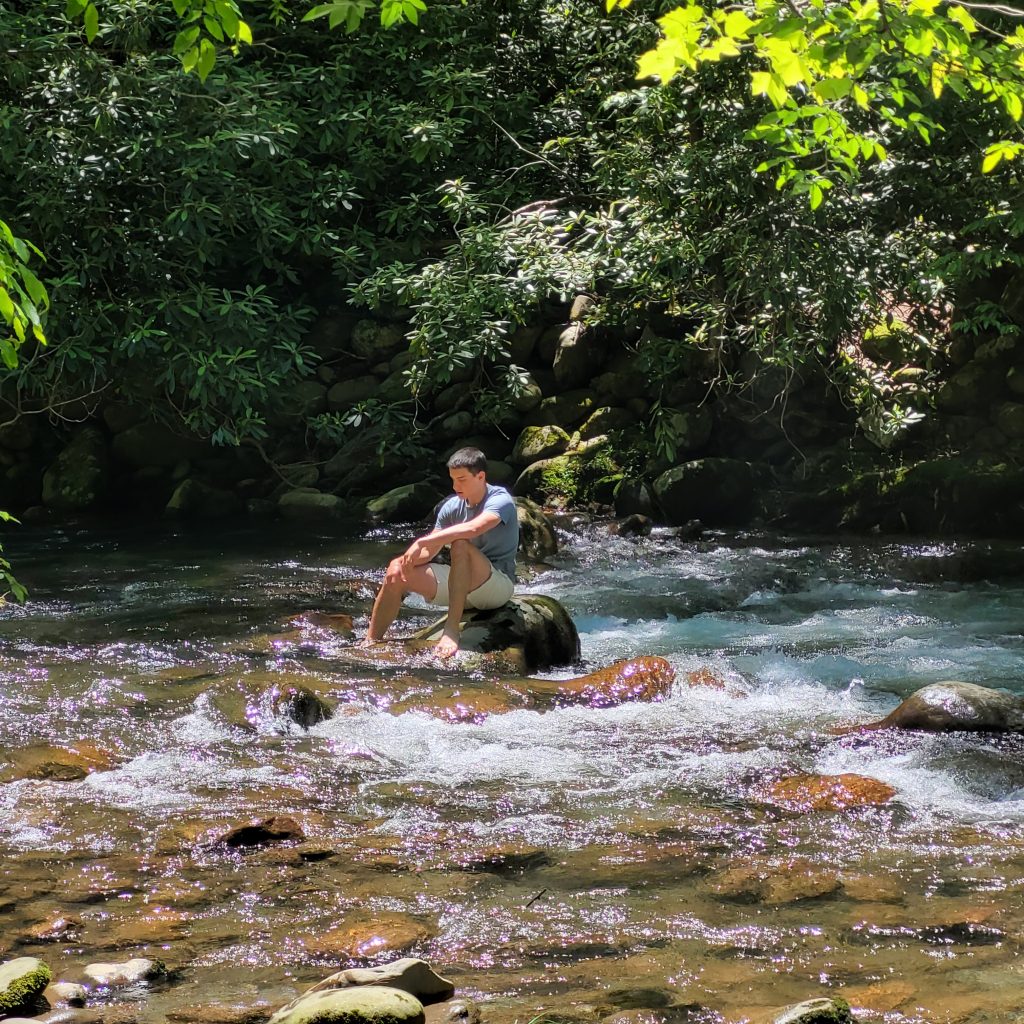 Teenage boy on a river rock
